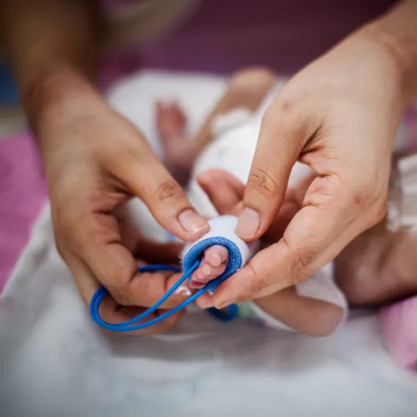 The foot of a newborn baby being examined by a doctor